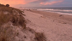 Een strand met duinen en een zonsondergang.