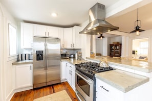 A modern kitchen with stainless steel appliances, white cabinetry, and a central island.