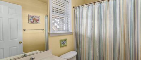 A bathroom with a toilet, sink, and a window with blinds.