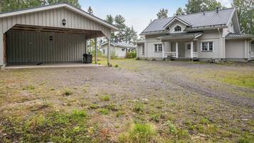 Een twee verdiepingen tellend huis met een overdekte garage en een voortuin met terras.