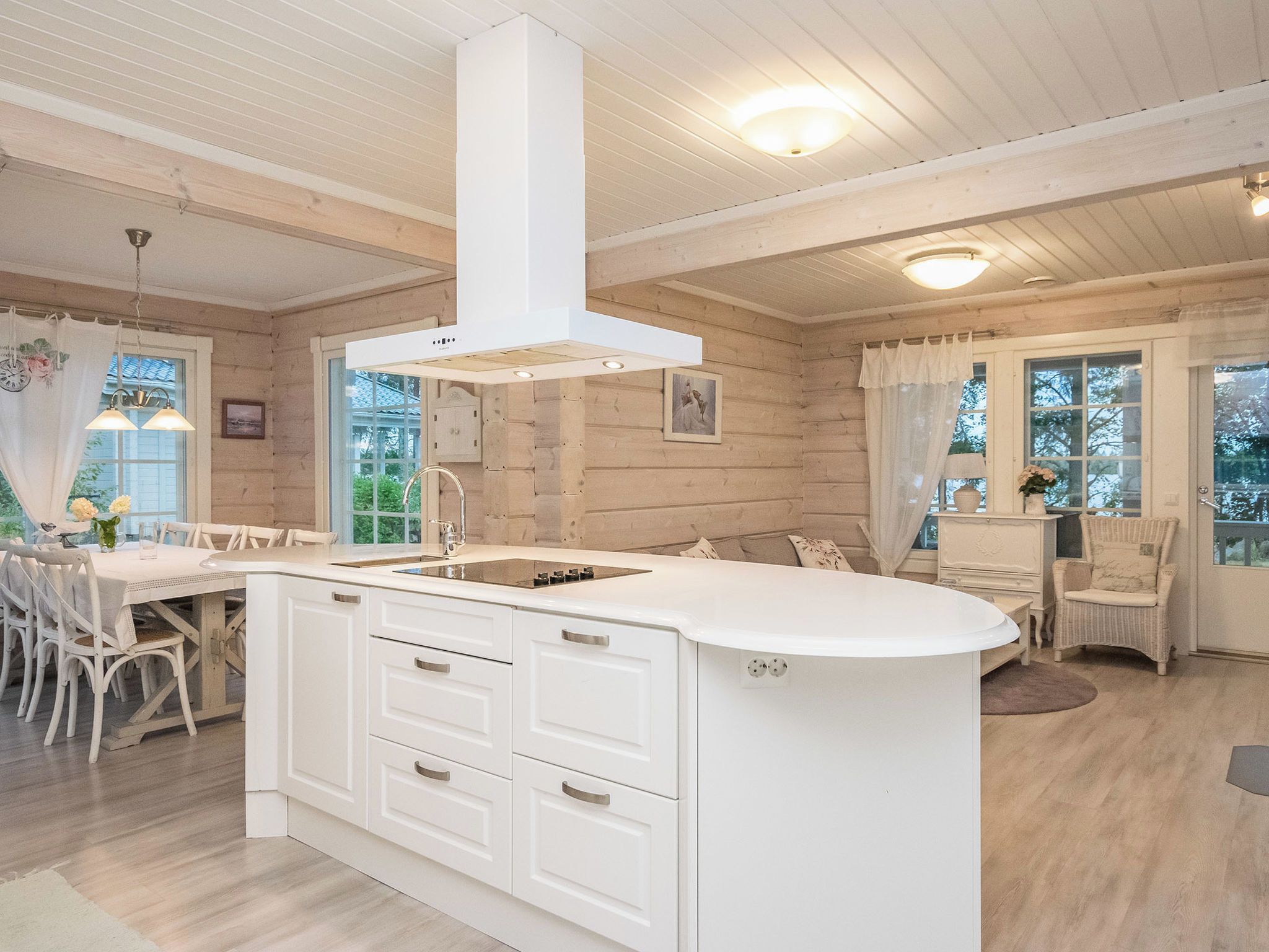 A modern kitchen with white cabinetry, a central island, and a built-in stove.