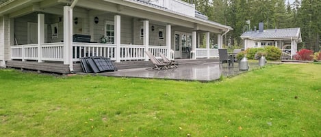 A two-story house with a covered porch, a deck, and a small garden.