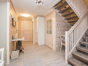 A wooden interior with a staircase, a white door, and a small table with a basket. - Tyssinniemi by Interhome (Punkaharju)