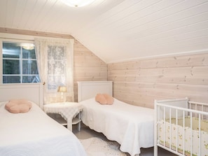 A room with two beds, a small table, and a crib. - Tyssinniemi by Interhome (Punkaharju)