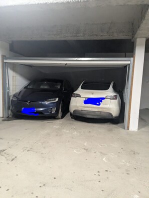 Dos autos estacionados dentro de un garaje con piso de concreto y paredes blancas.