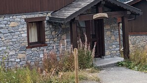 A wooden mountain lodge with stone foundation, wooden balcony, and a sign reading "Mountain Lodge".
