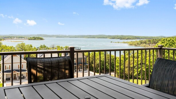 A deck with a view of a lake and surrounding greenery. - Lakeview Luxury • 3BR Majestic Condo • Sleeps 10 • Sunroom + Balcony (Branson)
