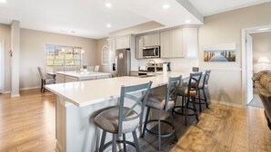 A modern kitchen with a central island, bar stools, and a dining area. - Lakeview Luxury • 3BR Majestic Condo • Sleeps 10 • Sunroom + Balcony (Branson)