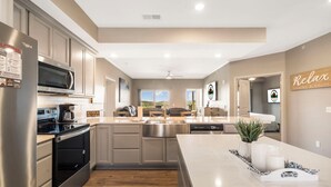 A modern kitchen with stainless steel appliances, a large island, and a view of the outdoors. - Lakeview Luxury • 3BR Majestic Condo • Sleeps 10 • Sunroom + Balcony (Branson)