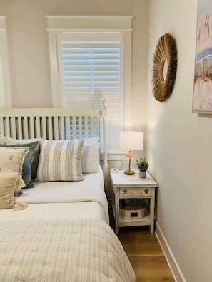 A bedroom with a bed, a nightstand, a lamp, and a window with blinds.