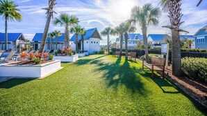 A well-maintained outdoor area with a lawn, seating, and palm trees.