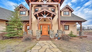 A large, two-story house with a stone facade, a prominent wooden entrance, and a stone pathway leading to the door. - Idyllic Florissant Cabin w/ Patio & Hot Tub! (Florissant)