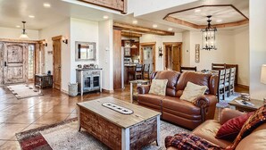 A spacious living area with a wooden coffee table, leather sofa, and a dining area with wooden chairs. - Idyllic Florissant Cabin w/ Patio & Hot Tub! (Florissant)