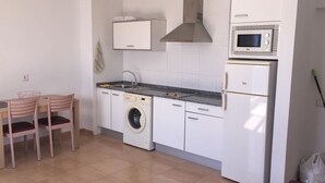 A compact kitchen with a washing machine, a microwave, and a sink. - FUERTEVENTURA PORT SEA (Morro Jable)