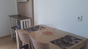 A dining area with a wooden table, two chairs, a TV mounted on the wall, and a power outlet on the wall. - FUERTEVENTURA PORT SEA (Morro Jable)