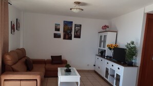 A living room with a brown sofa, a white coffee table, and a TV on a cabinet. - ESQUINZO POOL AND BEACH (Esquinzo)