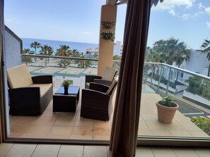 A balcony with wicker furniture, a small table with a plant, and a potted plant. - ESQUINZO: SWIMMING POOL AND BEACH (Esquinzo)