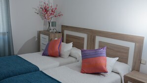 A double bed with two pillows, a bedside table, a lamp, and a vase with flowers. - ESQUINZO POOL AND BEACH (Esquinzo)