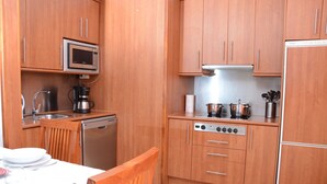 A compact kitchen with wooden cabinets, a microwave, a coffee maker, and a dishwasher. - ESQUINZO POOL AND BEACH (Esquinzo)