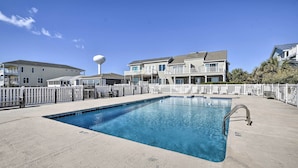 Una piscina rectangular con una escalera de metal, rodeada por una valla blanca.
