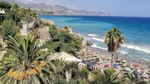 Ein Strand mit Palmen, einer felsigen Küstenlinie und einem klaren, blauen Meer.
