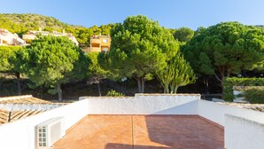 Terraço no telhado com piso de azulejos, cercado por árvores e edifícios.