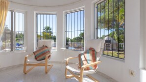 Quarto com duas cadeiras de balanço, grandes janelas e vista para o exterior.