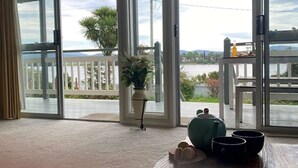Habitación con vista al agua, balcón con barandilla, planta en maceta y una mesa con tetera y tazas.