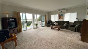 Un salón amplio con un ventanal, un sofá, una mesa de centro y un televisor.