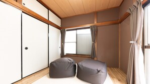 Une pièce avec un plafond en bois, une grande fenêtre avec des rideaux et deux fauteuils en forme de poire.