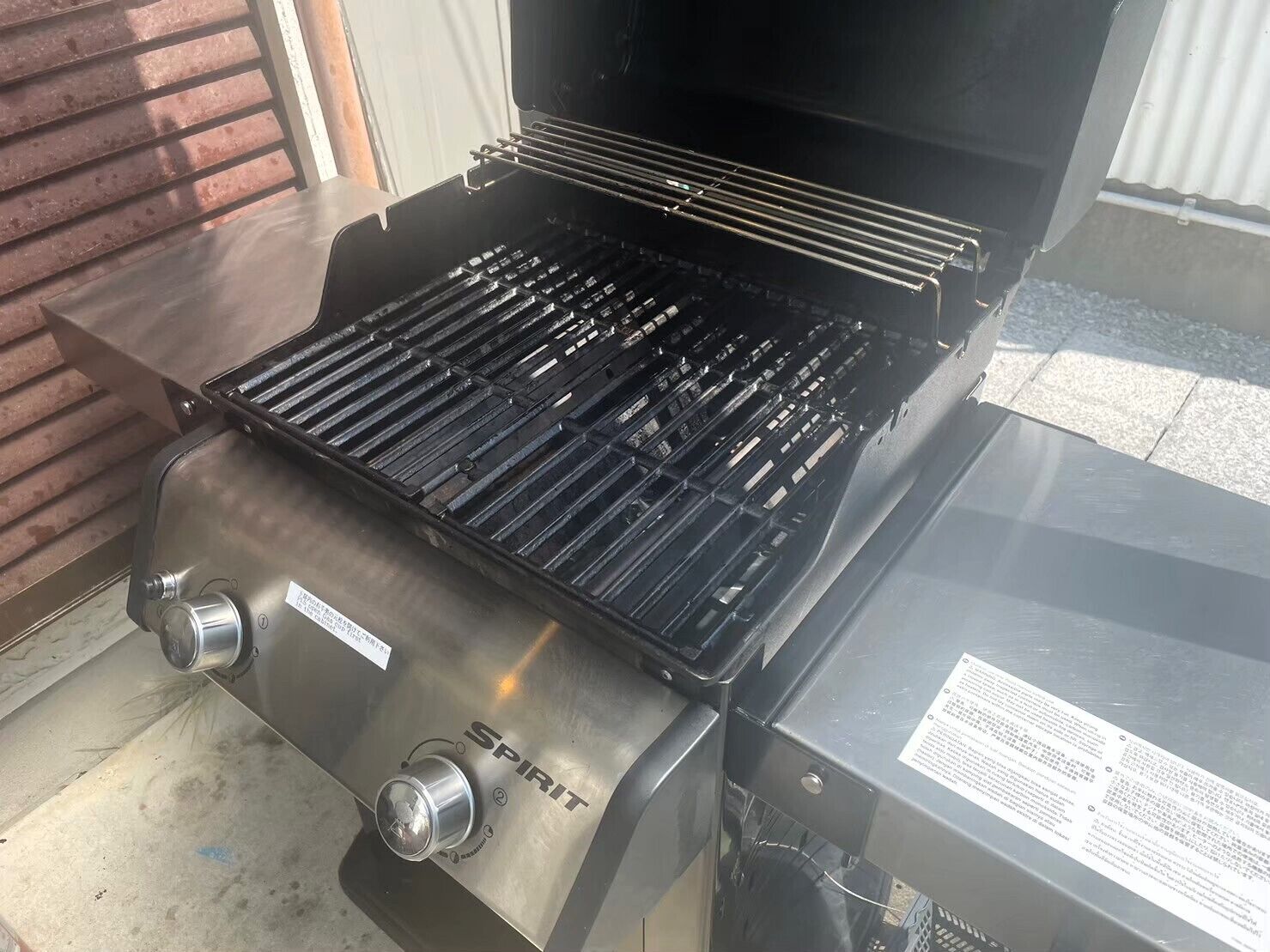 A stainless steel barbecue grill with a control panel and a gas tank.