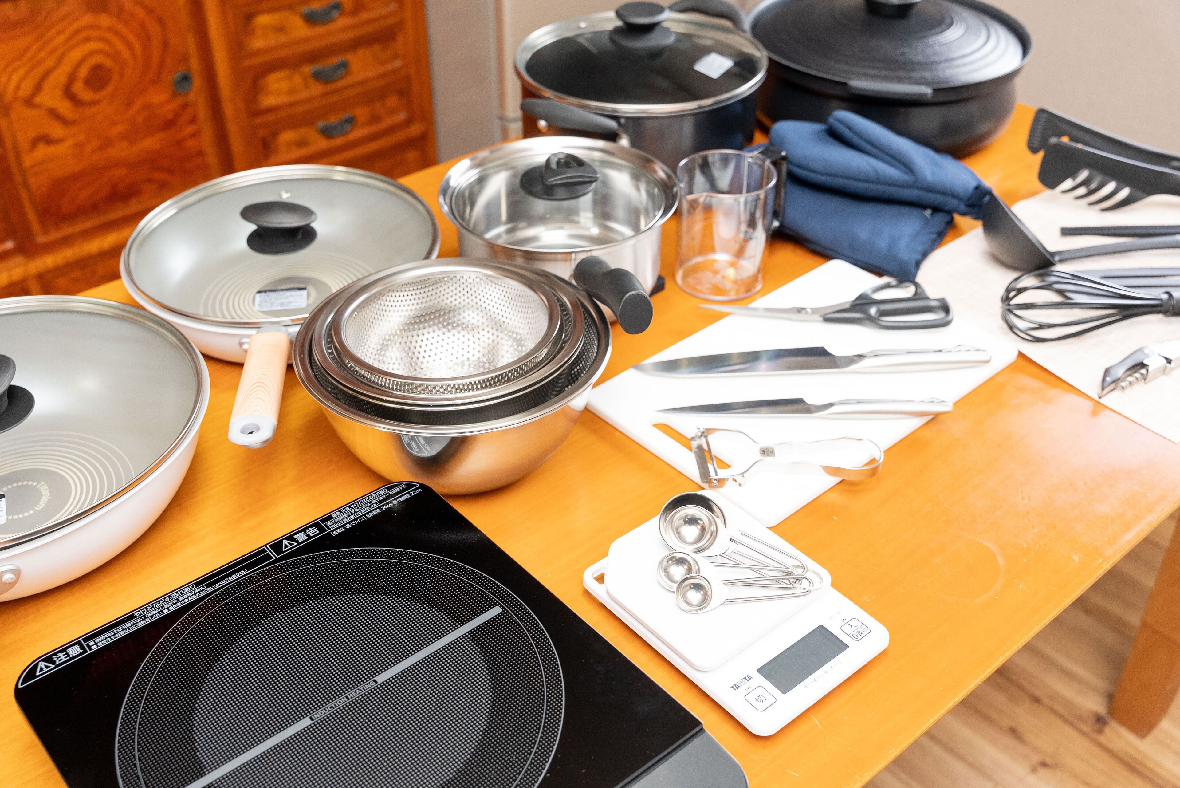 A kitchen counter with various cooking utensils, pots, pans, and a digital kitchen scale.