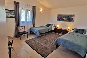 Ein Schlafzimmer mit zwei Betten, einem Sessel, einem Teppich und einem Bild an der Wand.