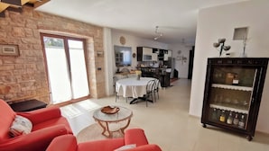 Een woonkamer met een rode bank, een klein rond tafeltje en een keuken op de achtergrond.