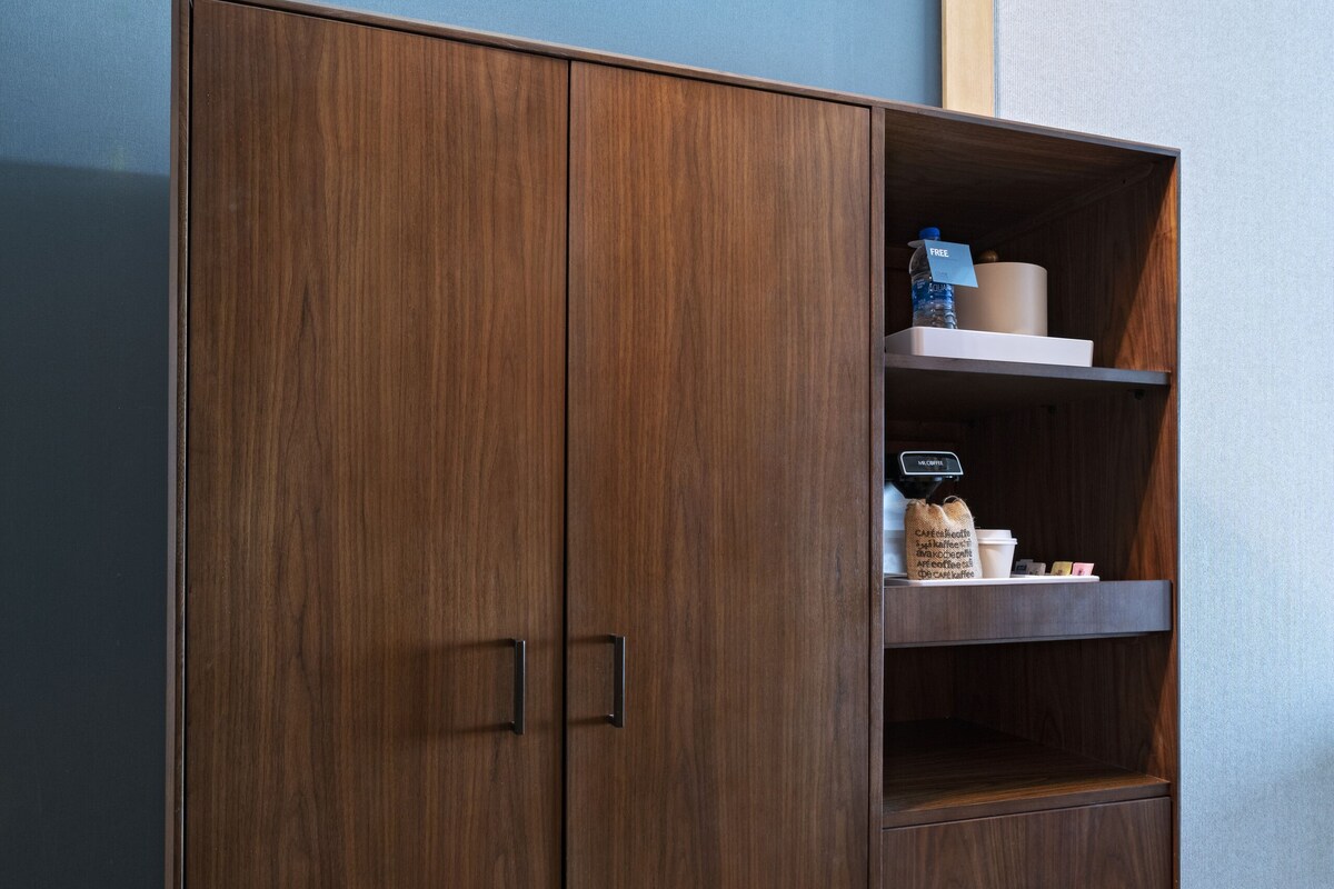 A wooden wardrobe with two doors and a shelf, placed against a blue wall.