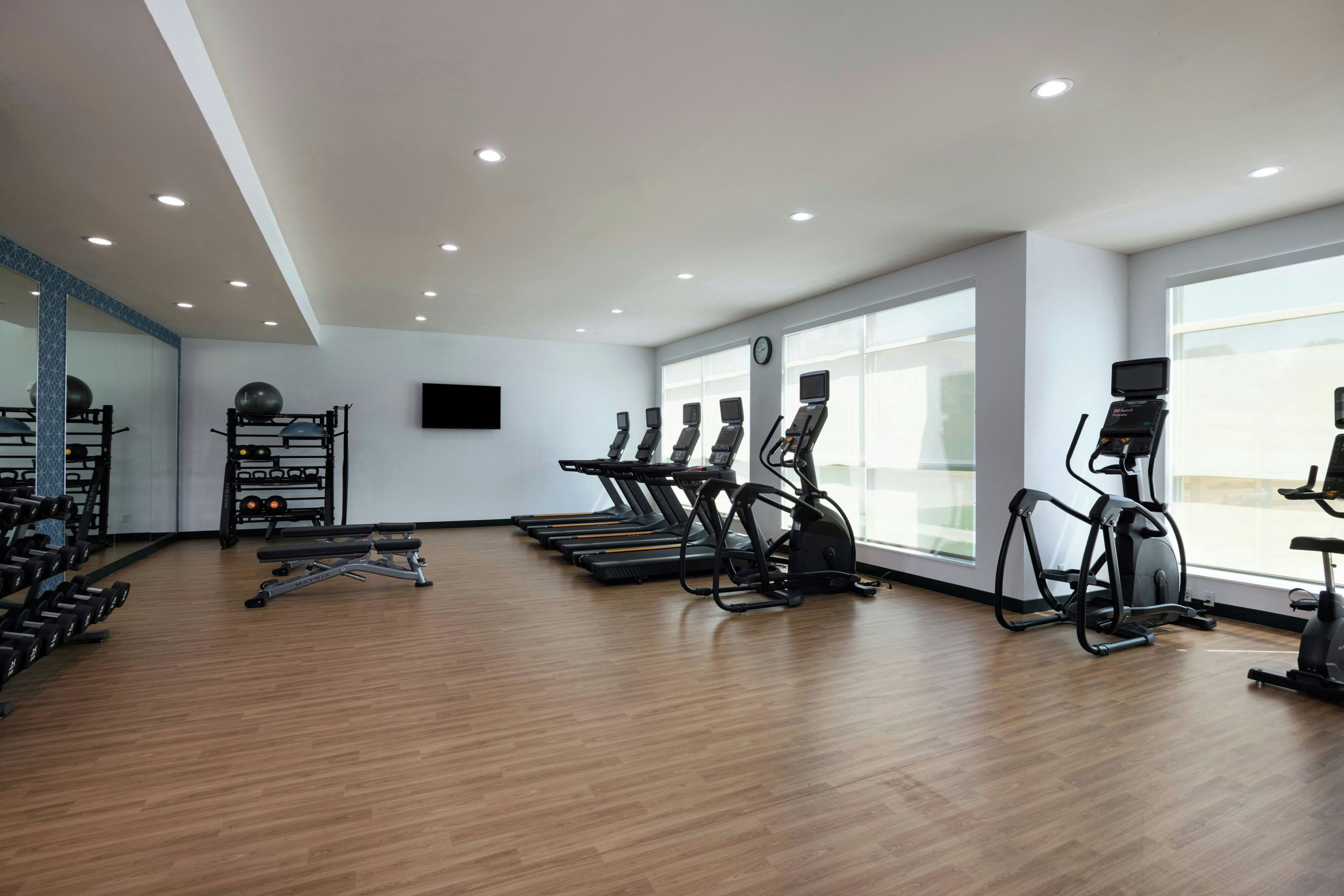 Un gimnasio con cintas de correr, elípticas y pesas libres.