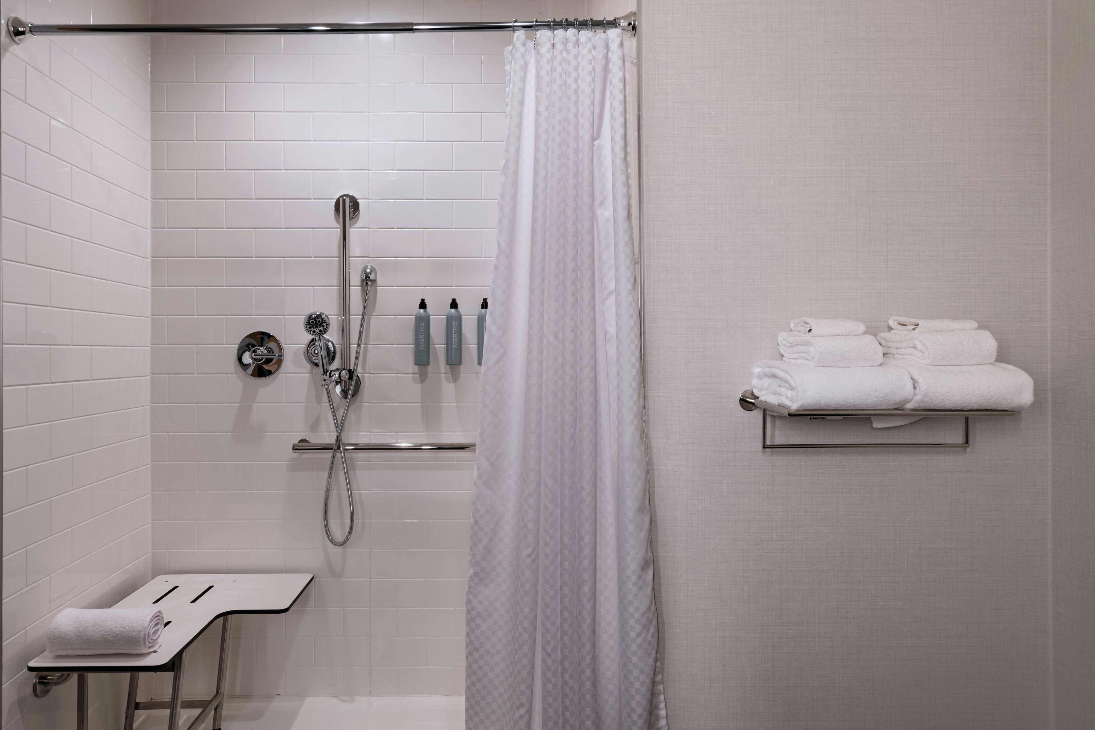 Un baño moderno con ducha, toallero y artículos de aseo.