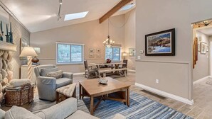 A spacious living room with a high ceiling, a dining area, and a large window. - Scenic Mountainside Home with Deck and Yard (Larkspur)
