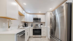 A modern kitchen with white cabinets, stainless steel appliances, and a central island. - Modern Retreat | Yoga Rm | Vast Yard | Near Denver (Westminster)