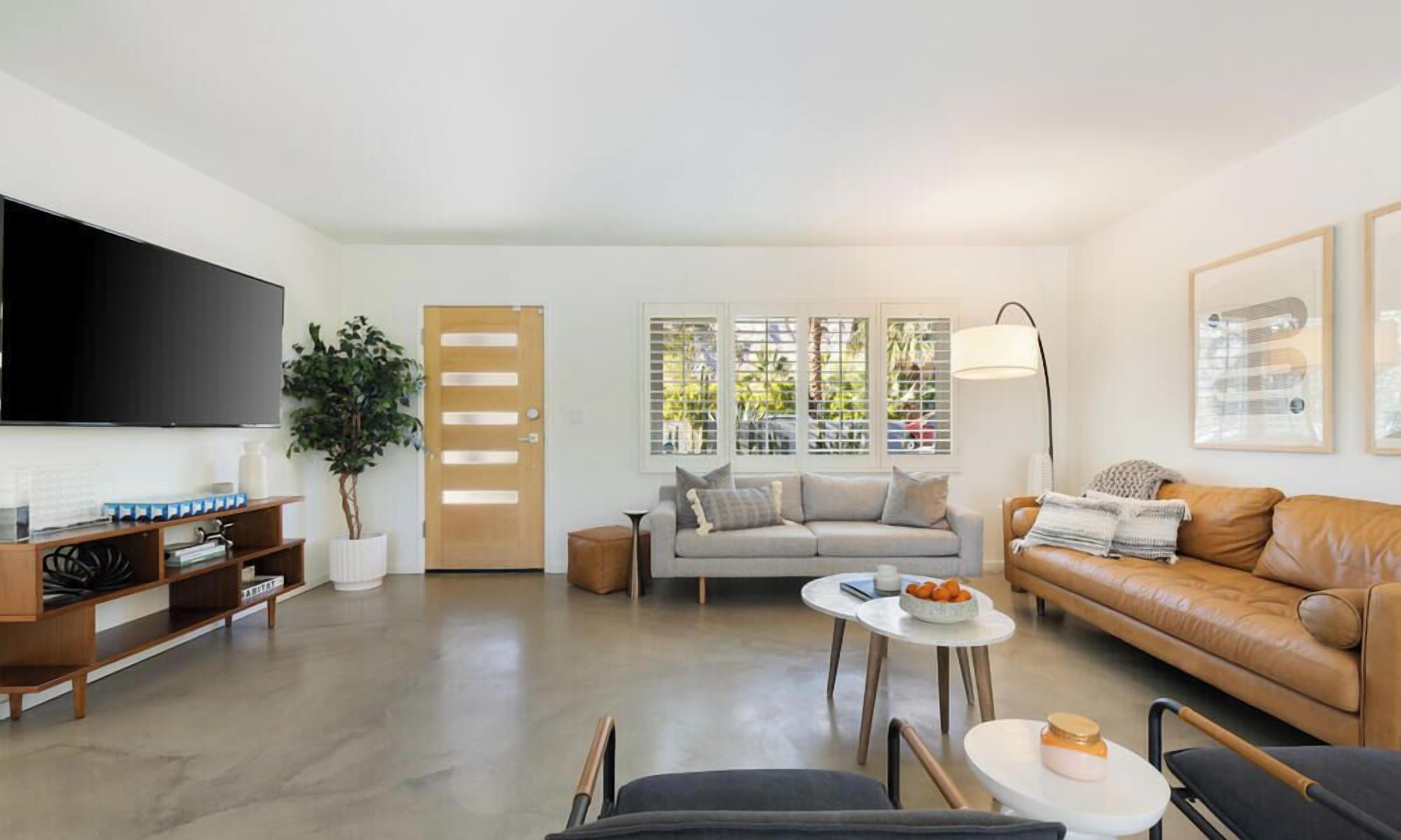 A modern living room with a flat-screen TV, a sofa, a coffee table, and a bookshelf.