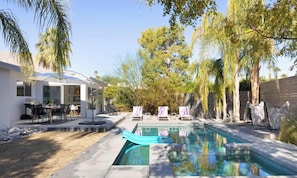 Piscina com espreguiçadeiras e área de estar ao ar livre.