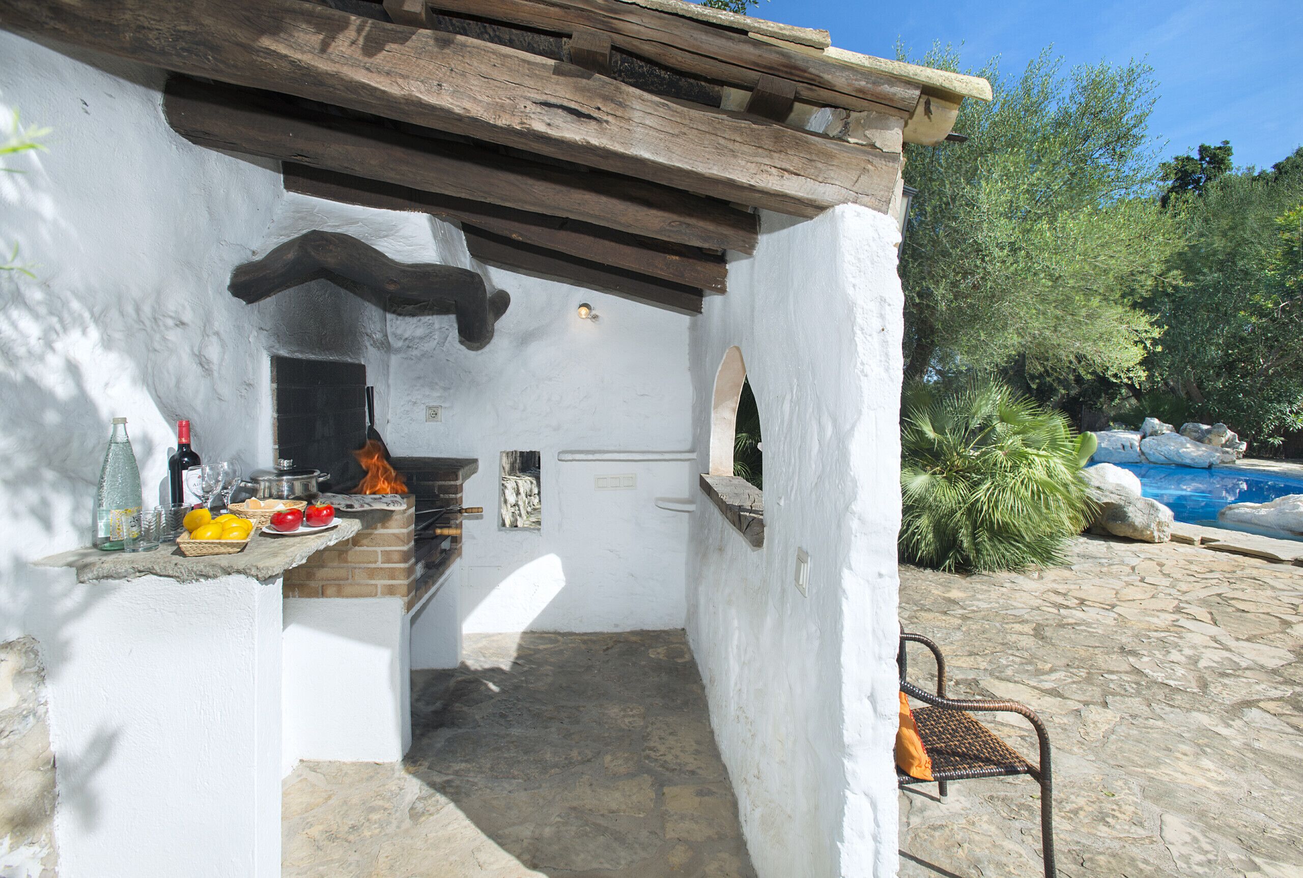 A rustic outdoor kitchen with a stone countertop, a brick oven, and a stone floor.