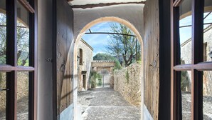 Un estrecho sendero de piedra que conduce a una puerta, flanqueado por muros de madera y un arco de metal.