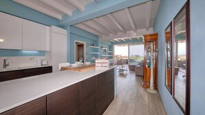 A modern kitchen with a large island, white cabinets, and a blue accent wall.