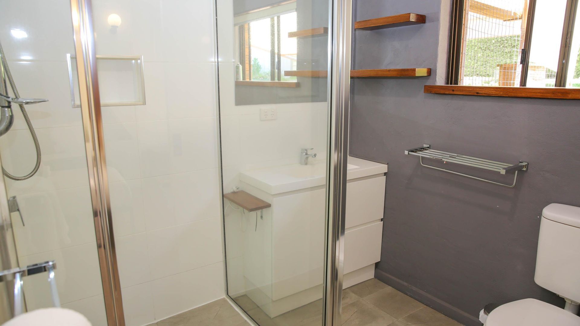 Une salle de bain moderne avec une douche à parois de verre, un lavabo blanc et des toilettes.