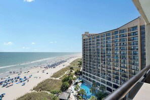 A hotel with a pool and beach view.