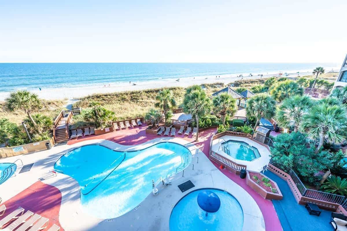 Un resort con varias piscinas, vista al mar y palmeras.