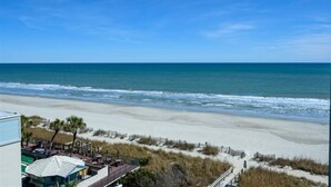 A beach view with a building in the foreground, a sandy beach, and the ocean. - Recently Renovated, Oceanfront View, Heated Pools! (Myrtle Beach)