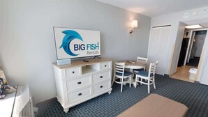 A room with a white dresser, a table, and two chairs. There is a sign on the wall that reads "BIG FISH Rentals". - Recently Renovated, Oceanfront View, Heated Pools! (Myrtle Beach)