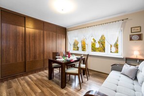 Un comedor con una mesa de madera dispuesta para cuatro personas, un sofá y una ventana con cortinas.
